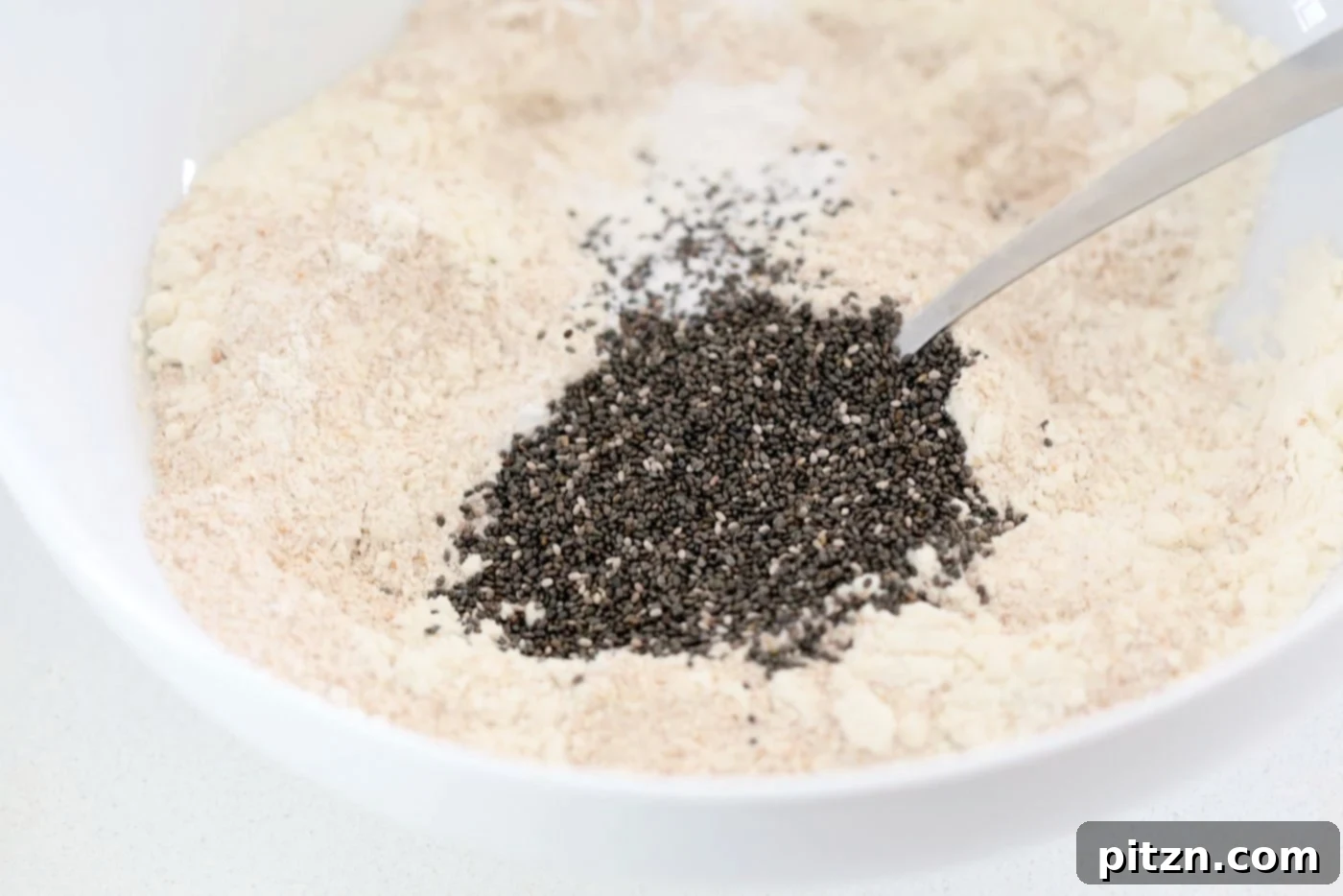 Dry ingredients thoroughly mixed in a white bowl for Our Vegan Turmeric Carrot Muffins, ready for wet ingredients