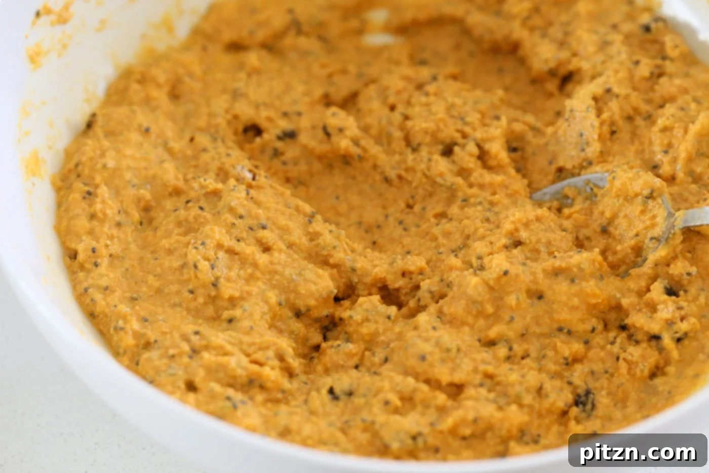Vegan Turmeric Carrot Muffins batter in a white bowl, ready for baking after adding optional dates or nuts