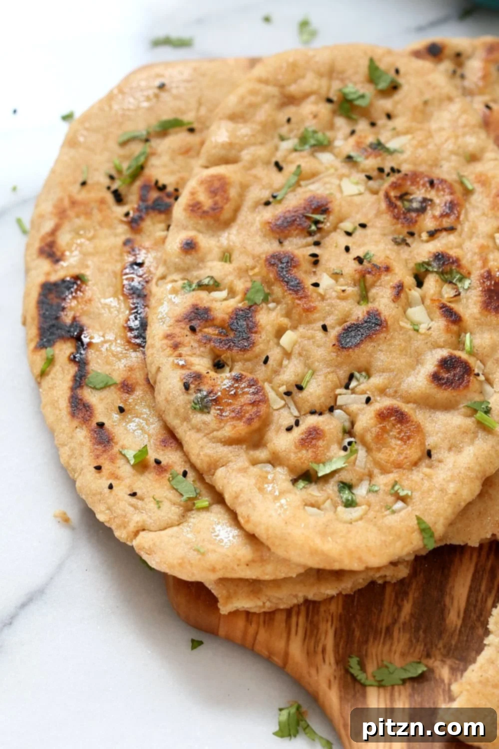 Close-up of freshly cooked Whole Wheat Naan Bread, showing golden brown spots and soft, puffy texture, ready to be served.
