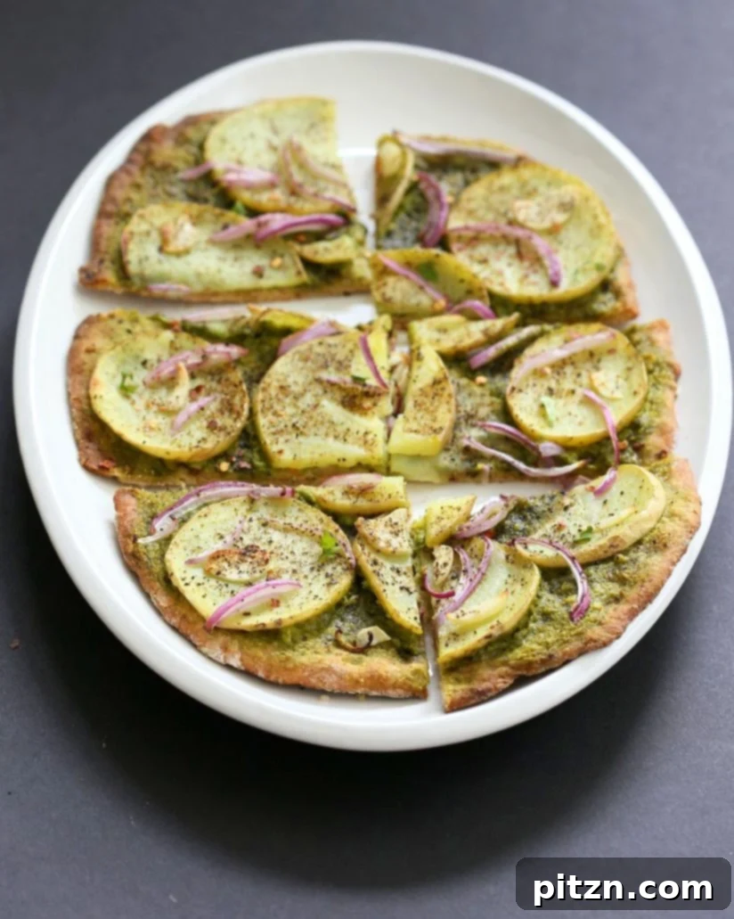 Vegan Basil Spinach Potato Pesto Pizza 3 Up close image of Easy Potato Pesto Pizza with a thin crust, showing basil spinach pesto, potato slices, onion, and garlic before baking.