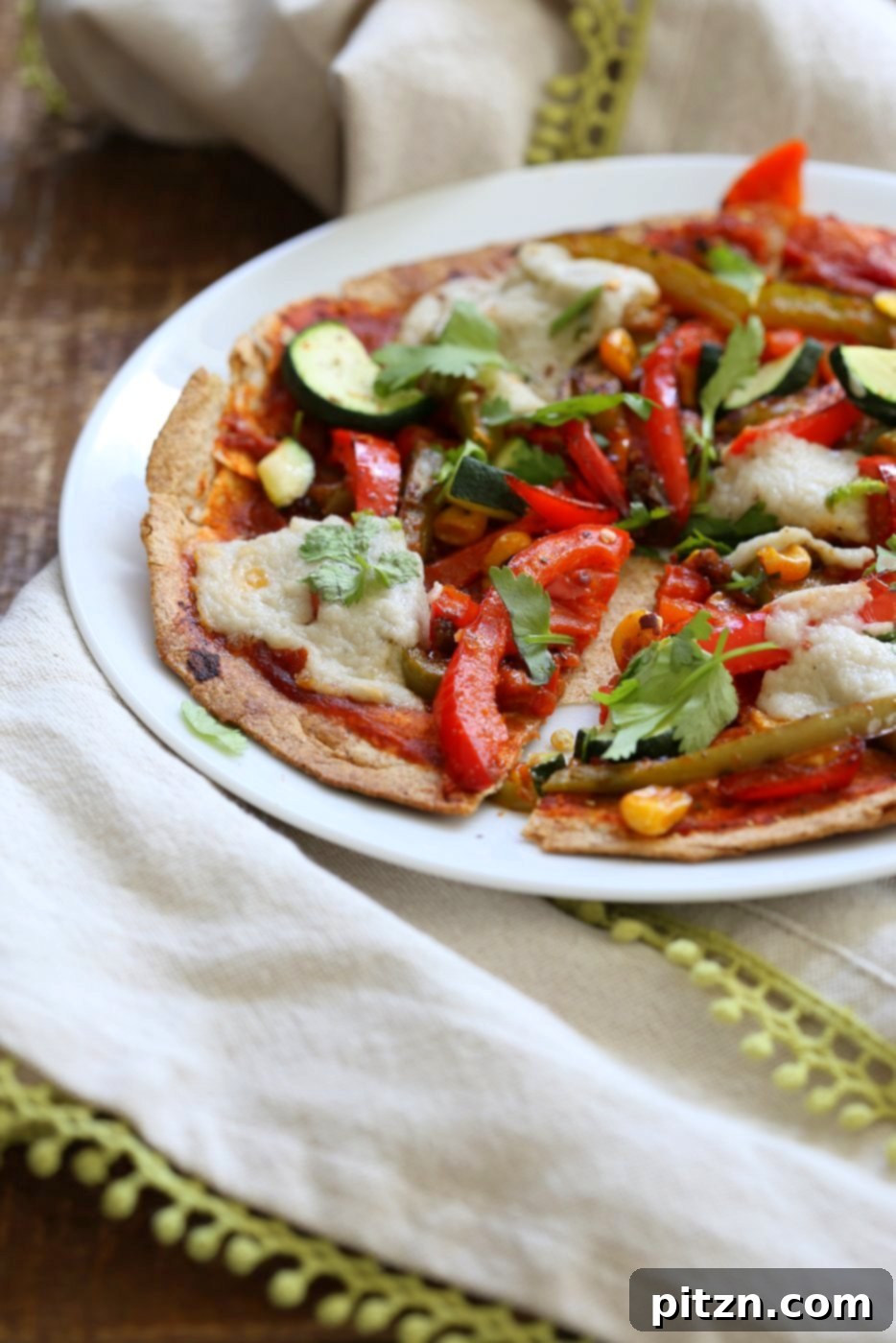Overhead shot of two Vegetable Fajita Tortilla Pizzas on a wooden board, garnished with fresh cilantro and a sprinkle of red pepper flakes, ready to be served. Highlighting a quick and healthy vegan meal option.