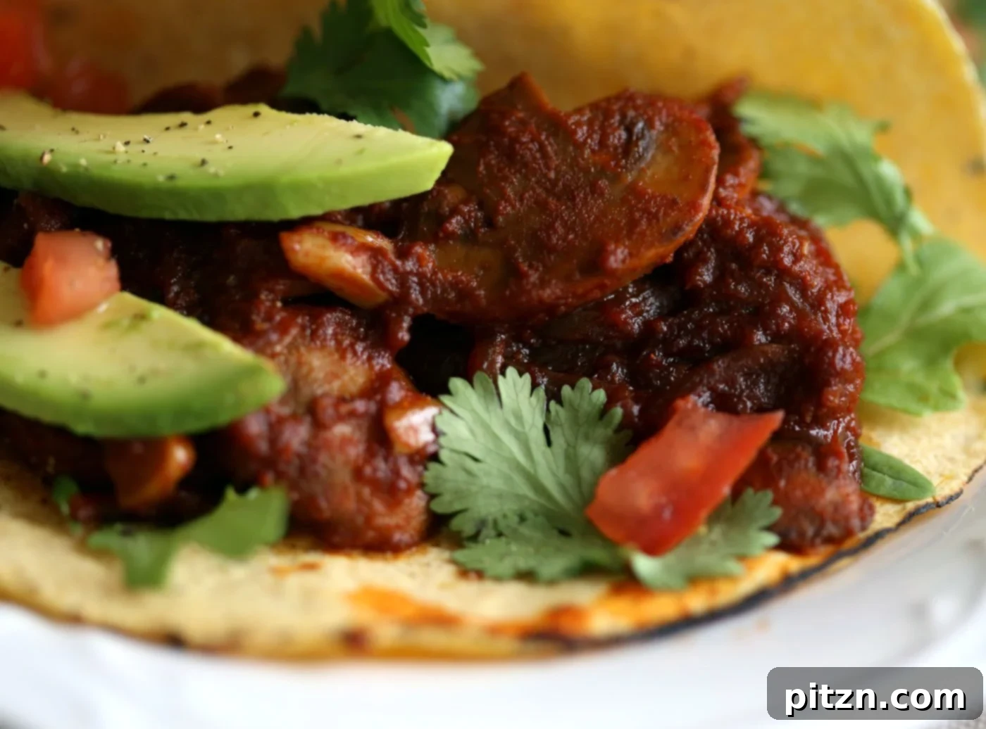 Vegan Barbacoa Mushroom Tacos served with avocado, salsa, and greens.