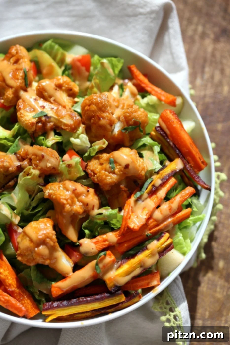 A vibrant and appetizing close-up of the Peanut Butter Cauliflower and Carrot Bowl, highlighting the contrast between the roasted vegetables and fresh greens, drizzled with a rich peanut sauce. This image emphasizes the freshness and deliciousness of this vegan, gluten-free recipe.