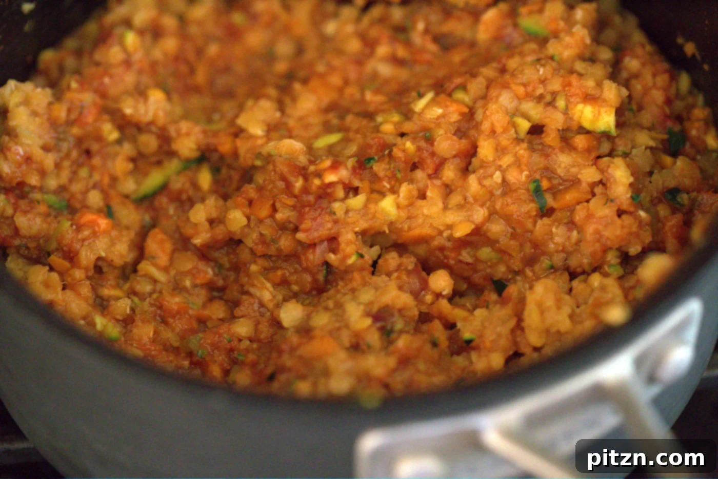 Cajun Spiced Smoky Vegan Sloppy Lentils 7 Onions, garlic, carrots, and zucchini sautéing in a skillet, forming the flavorful base for the smoky vegan sloppy joes.