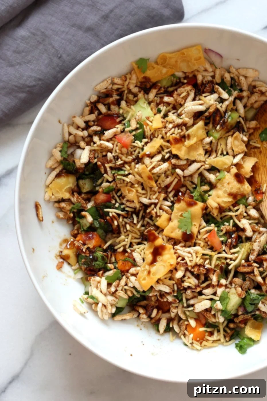 A close-up of a serving of Sweet Potato Bhel, a vibrant and healthy Indian street food salad with sweet potatoes, puffed rice, fresh mint, and zesty tamarind chutney. Vegan and easily made gluten-free and nut-free for a quick snack. VeganRicha.com