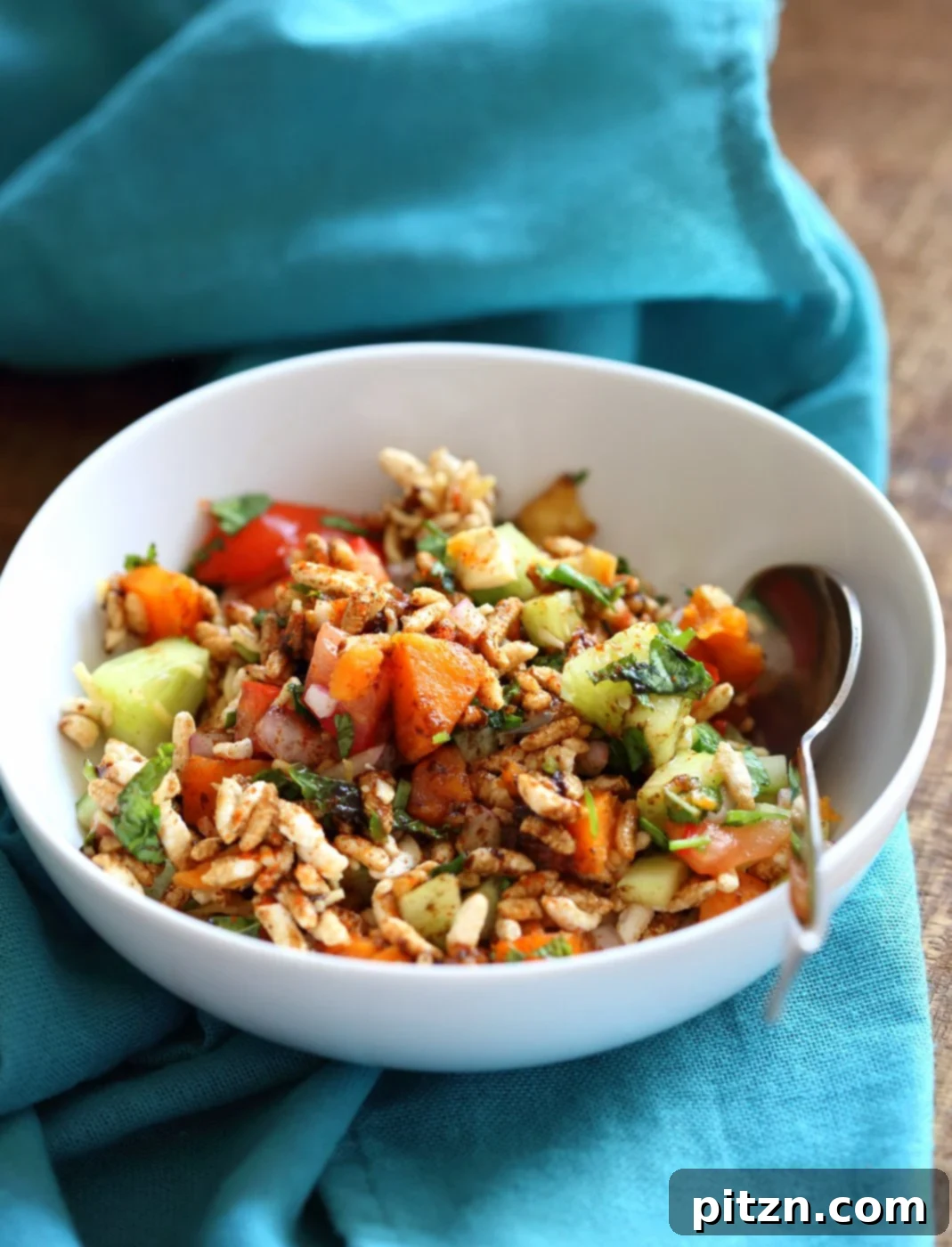 A beautiful top-down shot of Sweet Potato Bhel, an Indian street food snack salad featuring puffed rice, sweet potato, fresh herbs like mint and cilantro, and a tangy tamarind chutney. This healthy and quick recipe is vegan, gluten-free, and nut-free friendly. VeganRicha.com