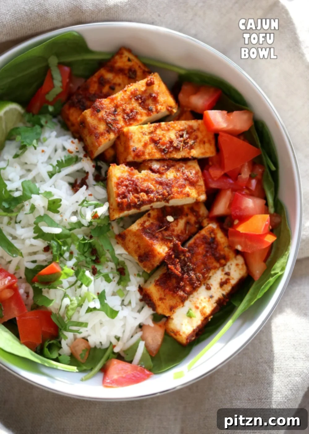 A close-up view of the ingredients for the Cajun Tofu Bowl, showcasing the richly spiced tofu, fluffy cilantro lime rice, and fresh garnishes before assembly.