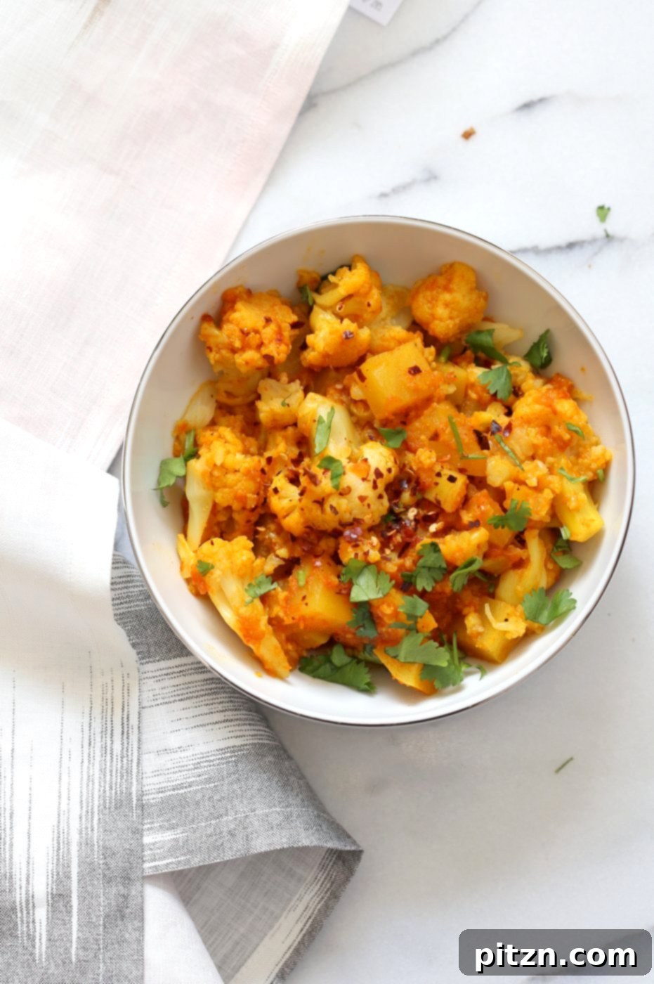 Instant Pot Aloo Gobi - Curried Potato Cauliflower. A beautifully garnished bowl of Indian potato and cauliflower curry with fresh cilantro and lemon. Vegan, Gluten-free, Soy-free, Nut-free recipe.