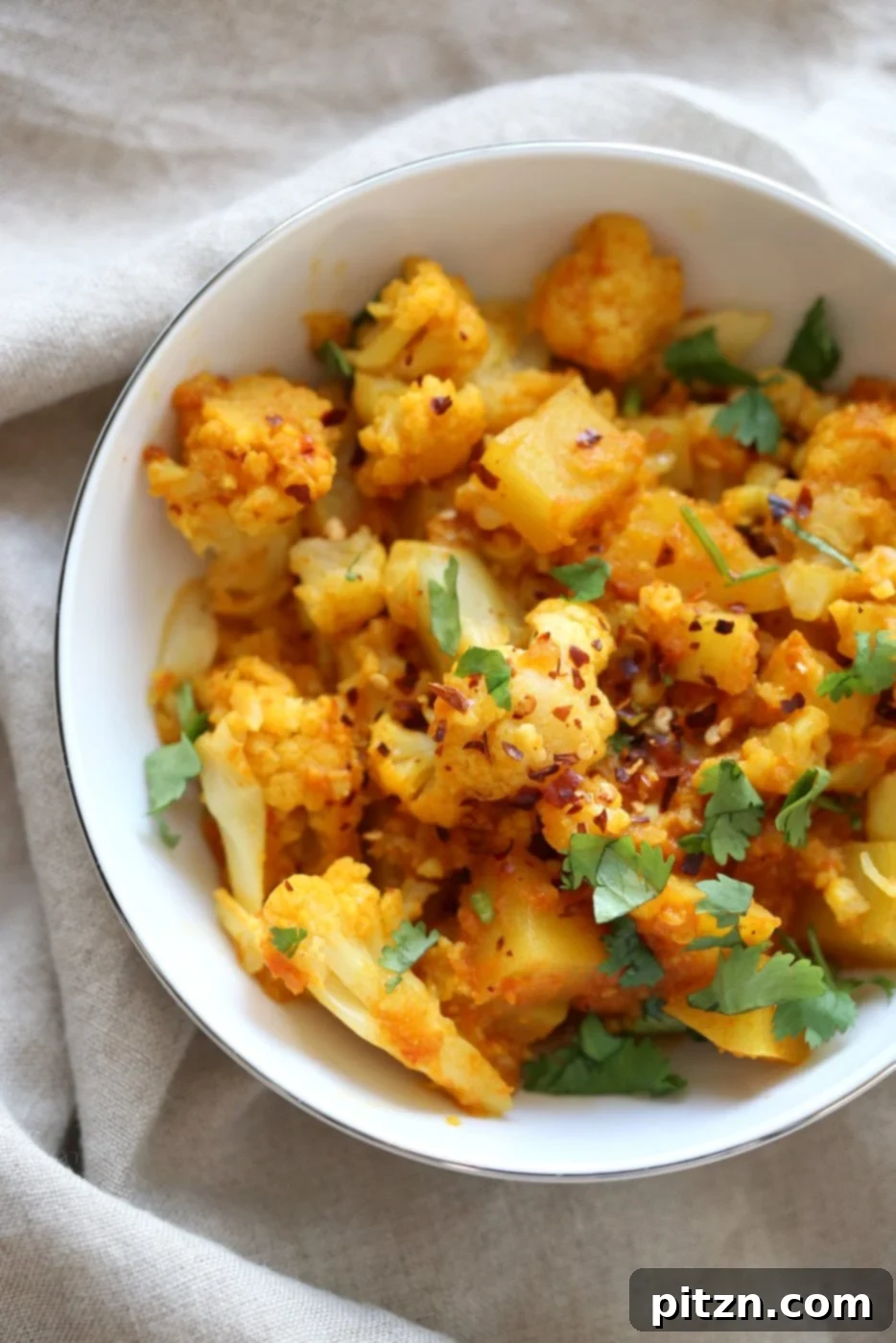 Instant Pot Aloo Gobi - Curried Potato Cauliflower. A bowl of freshly made Indian potato and cauliflower curry, garnished and ready to eat. Vegan, Gluten-free, Soy-free, Nut-free recipe.