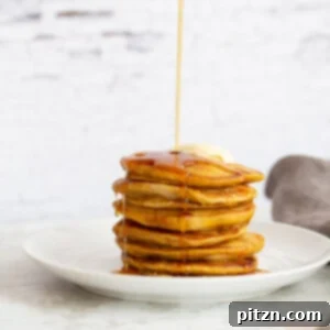 Stack of fluffy vegan pumpkin pancakes drizzled with maple syrup.