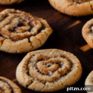 Pumpkin spice roll cookies on a rustic wooden tray, resembling cinnamon rolls in cookie form.