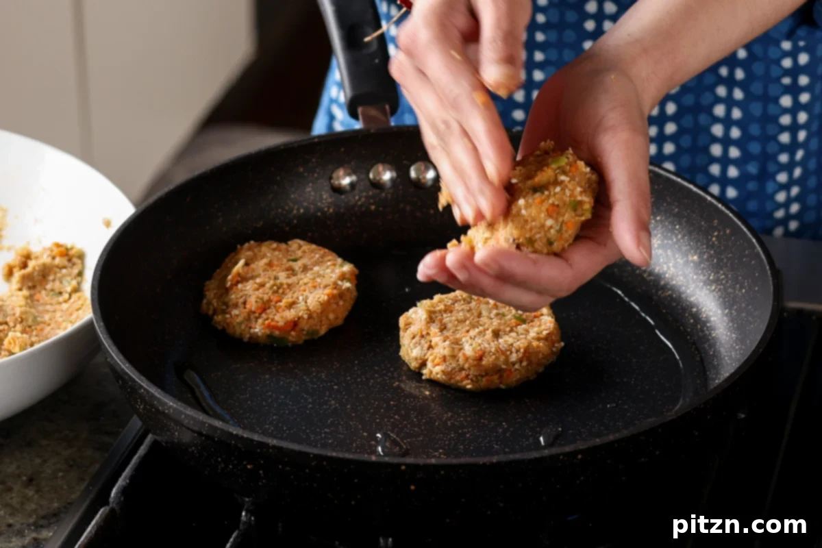 Placing BBQ lentil burger patties into a hot frying pan to achieve a crispy, golden-brown exterior.