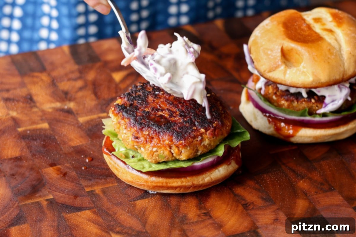 Adding a cooked BBQ lentil patty and a spoonful of creamy coleslaw to a burger bun, creating a visually appealing layer.