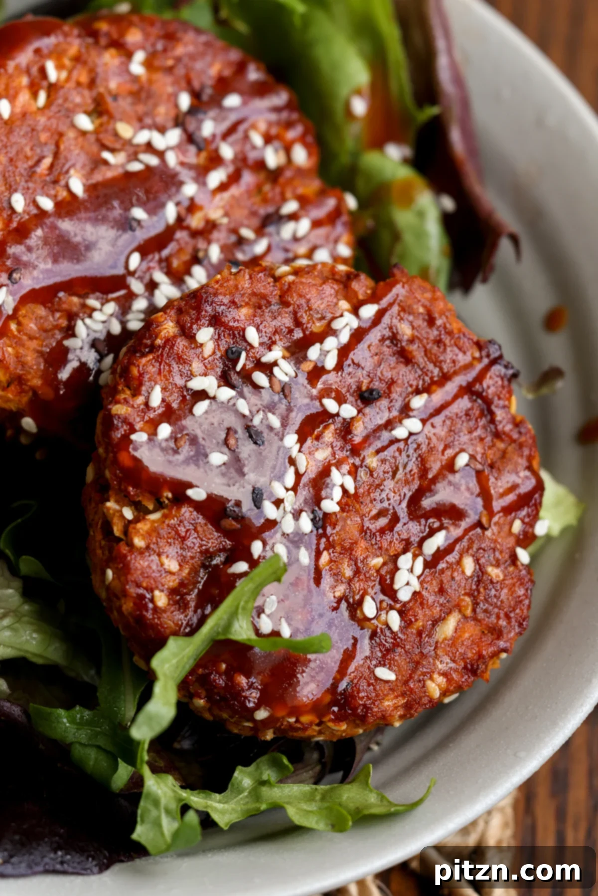Two BBQ lentil burger patties beautifully arranged on a fresh green salad, highlighting a lighter serving option.