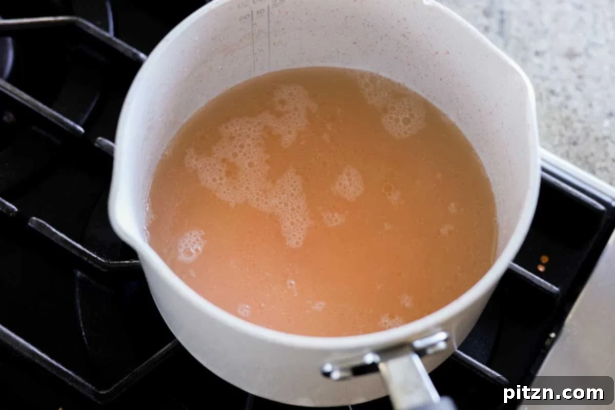Red lentils cooking on the stovetop in a saucepan, absorbing water to become tender.