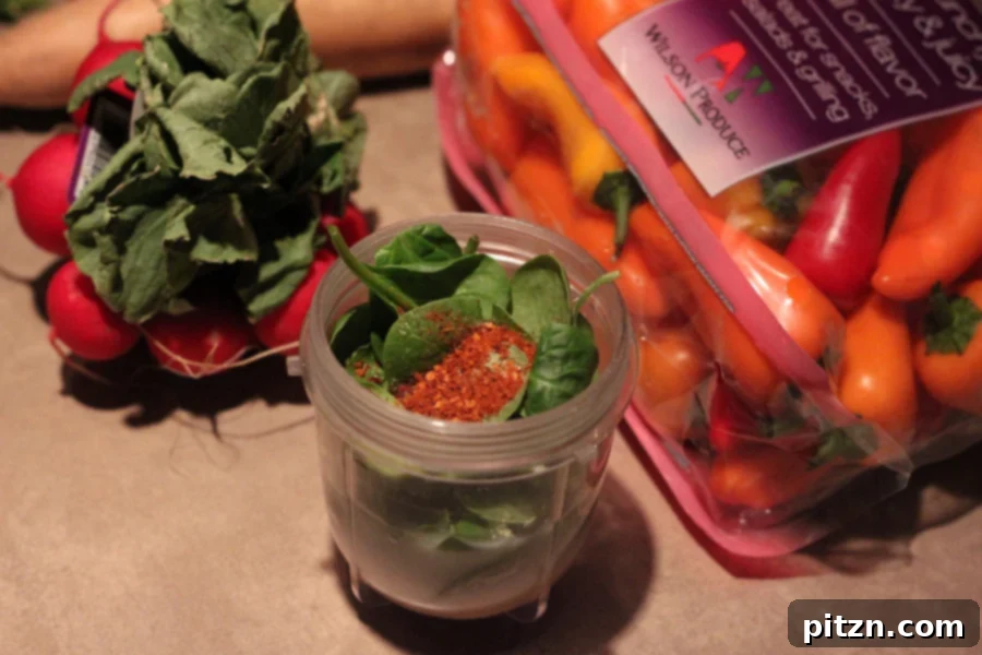 spinach and cayenne pepper in a magic bullet blender for making vegan alfredo sauce