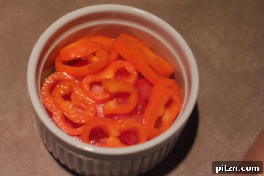 sliced mini bell peppers in a small white casserole dish, ready for next layer