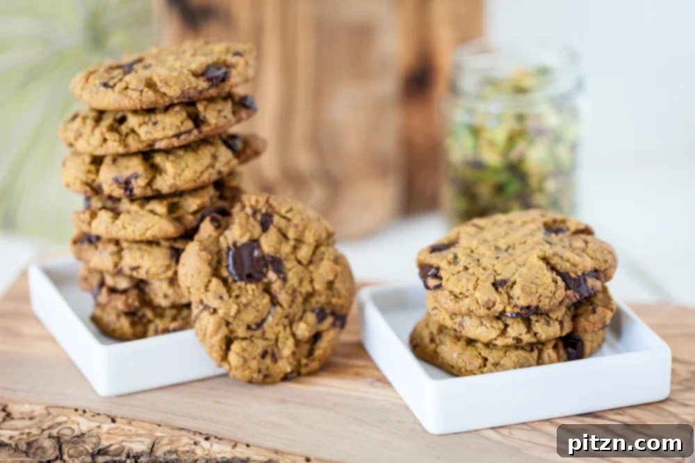 An easy Pistachio Cookies recipe with pistachio butter as the main ingredient and chocolate chunks for extra good flavor! Vegan, Gluten Free. Stack of chocolate chunk pistachio cookies on two white plates on wooden board