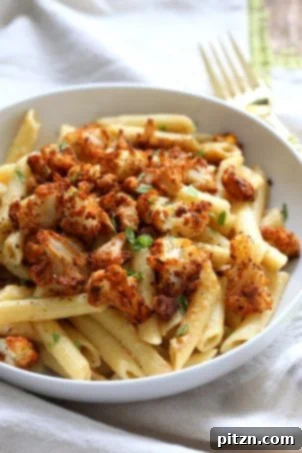 Creamy vegan garlic pasta topped with roasted Cajun cauliflower, offering a nut-free and gluten-free friendly dinner option.