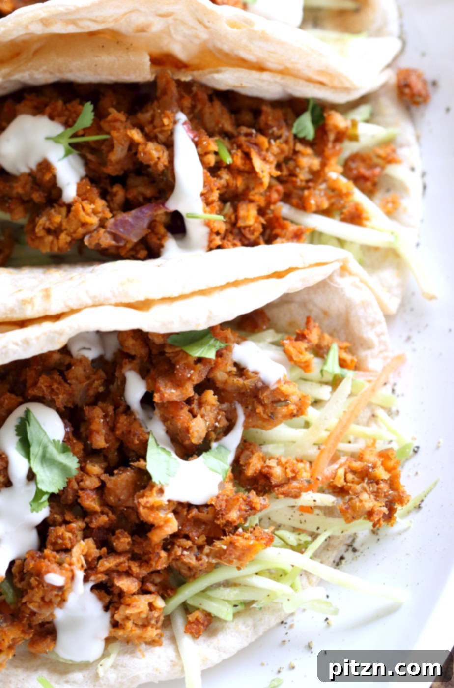 Two hands holding a fresh Mango BBQ Soy Curls taco, highlighting the delicious filling and homemade appeal. This vegan, gluten-free, and oil-free recipe is perfect for any meal.