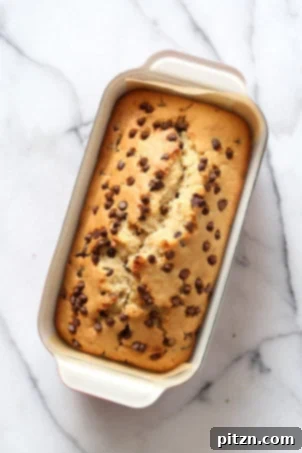 Decadent Vegan Chocolate Chip Cake 6 A beautiful loaf pan filled with Vegan Chocolate Chip Cake batter, ready for baking on a marble surface.