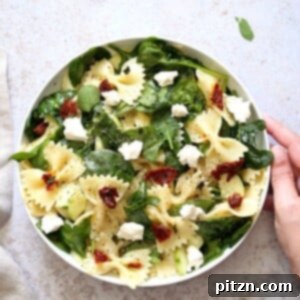Tuscan Pasta Salad with Zesty Lemon Vinaigrette 6 A beautifully presented bowl of Tuscan Pasta Salad on a light worktop.