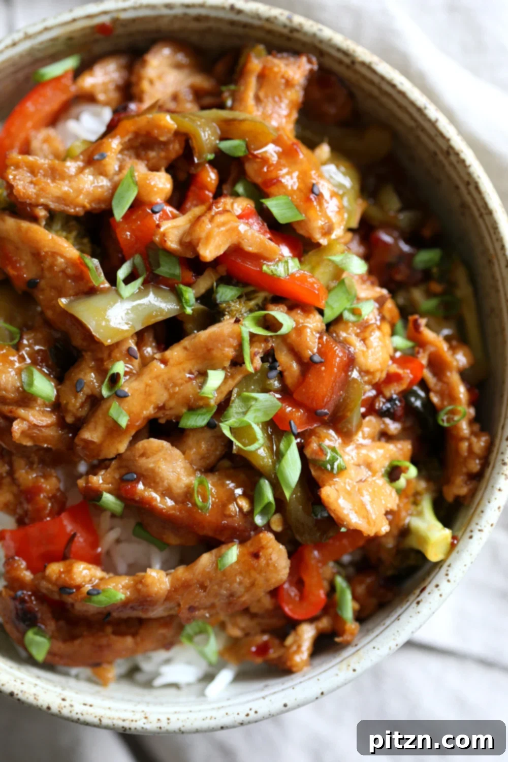 Crispy Vegan General Tso's Soy Curls 2 Vegan General Tso Soy curls in a speckled bowl, garnished with green onions and sesame seeds