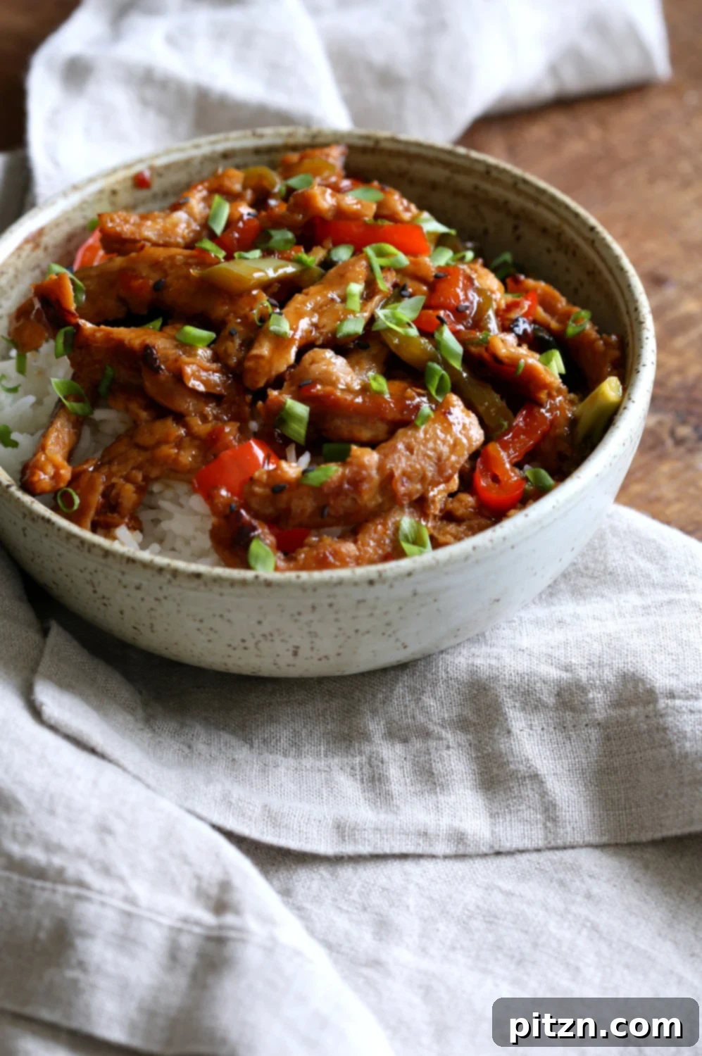 Crispy Vegan General Tso's Soy Curls 3 Close-up of vegan General Tso Soy curls in a speckled bowl, showing vibrant sauce and textures