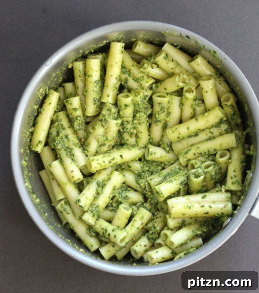 Vibrant Vegan Pesto Pasta with Smoky Charred Broccoli 7 A food processor containing basil, spinach, sunflower seeds, pecans, garlic, salt, nutritional yeast, and lemon zest for pesto preparation.