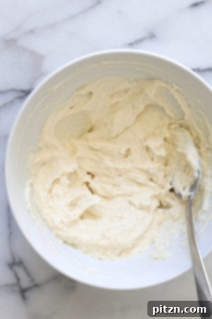 Velvety Vegan Malai Burfi Fudge 5 The smooth, whipped mixture of vegan cream cheese and butter in a white bowl, ready for dry ingredients.