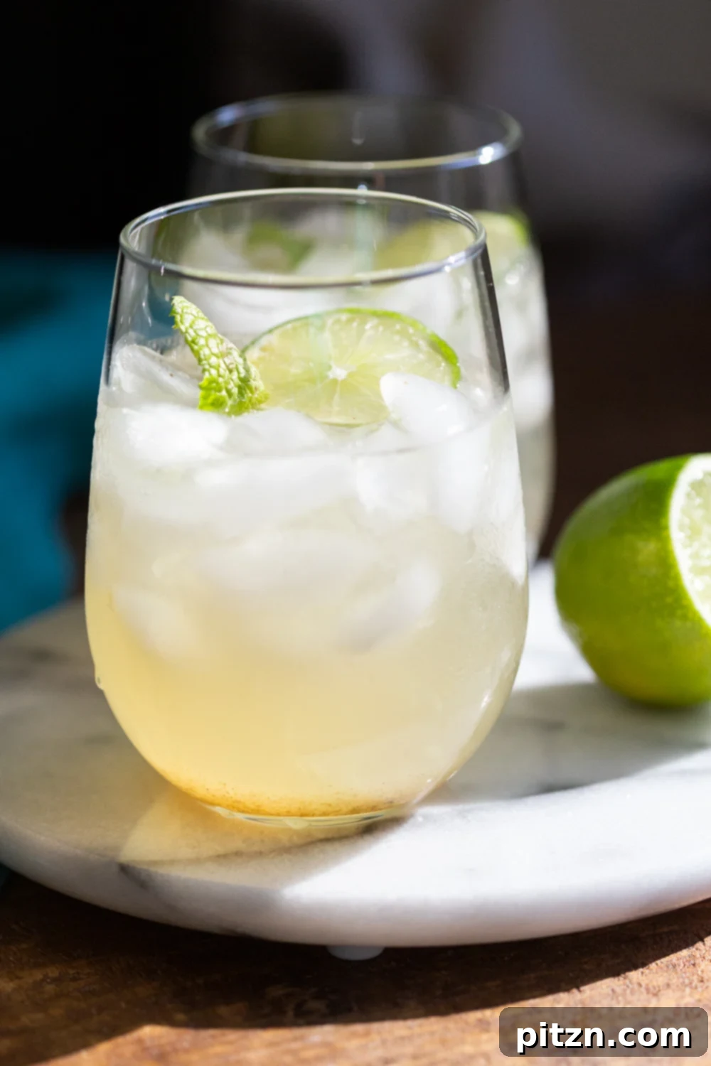 Shikanji Zesty Indian Lemonade 4 Shikanji or Nimbu Pani, a spiced Indian lemonade in three glasses, garnished with lime and mint, on a wooden surface.
