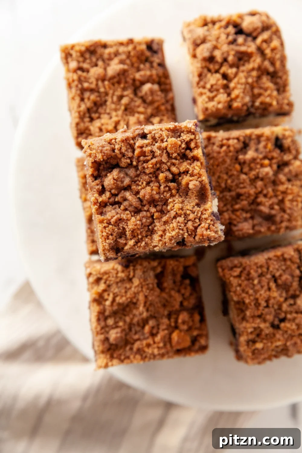 Vegan Blueberry Buckle slices on a white cake stand
