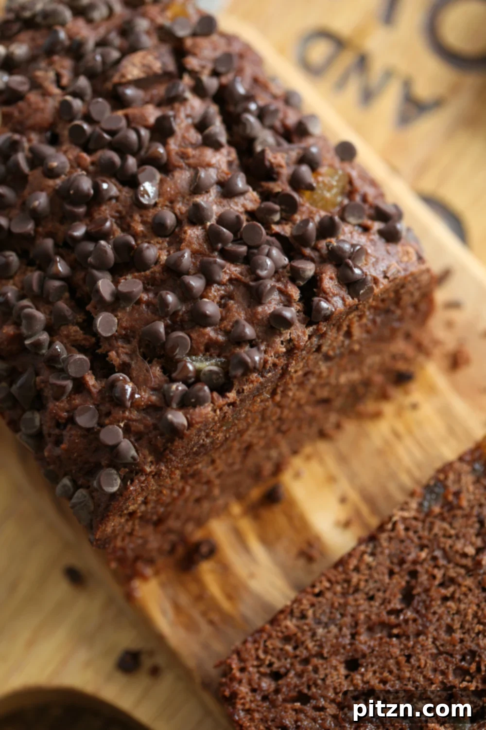 Spiced Vegan Chocolate Gingerbread Delight 3 Sliced Vegan Chocolate Gingerbread Cake showing its soft, moist crumb and melted chocolate chips against a white backdrop.