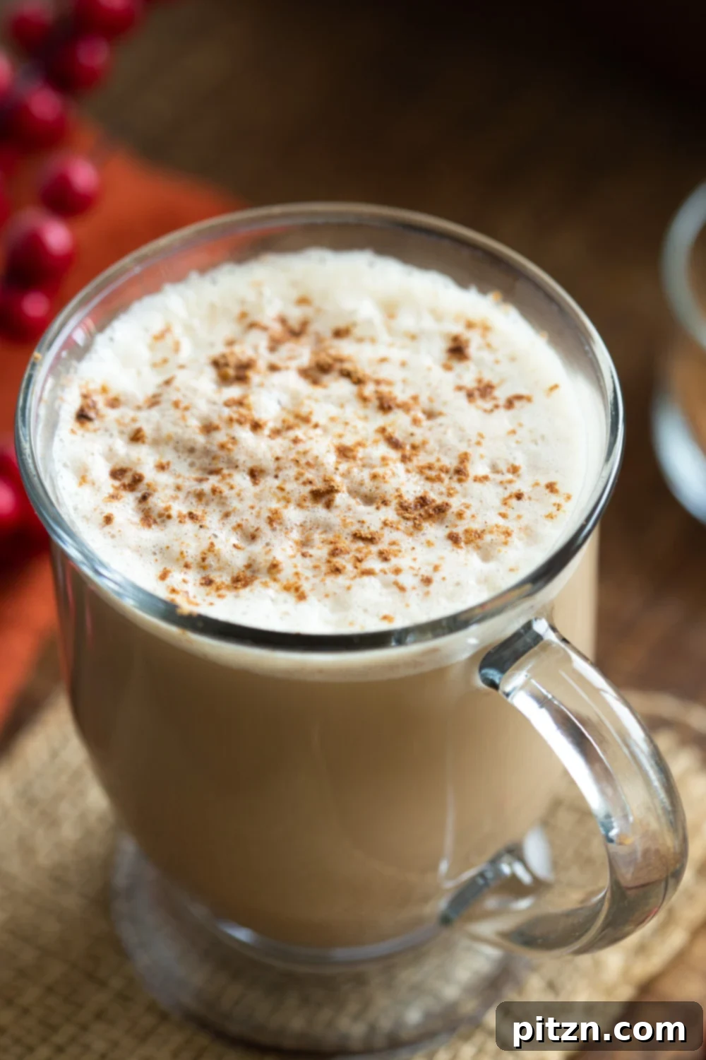 A beautifully styled mug of creamy vegan gingerbread latte, topped with whipped cream and a sprinkle of spices, set against a cozy background.