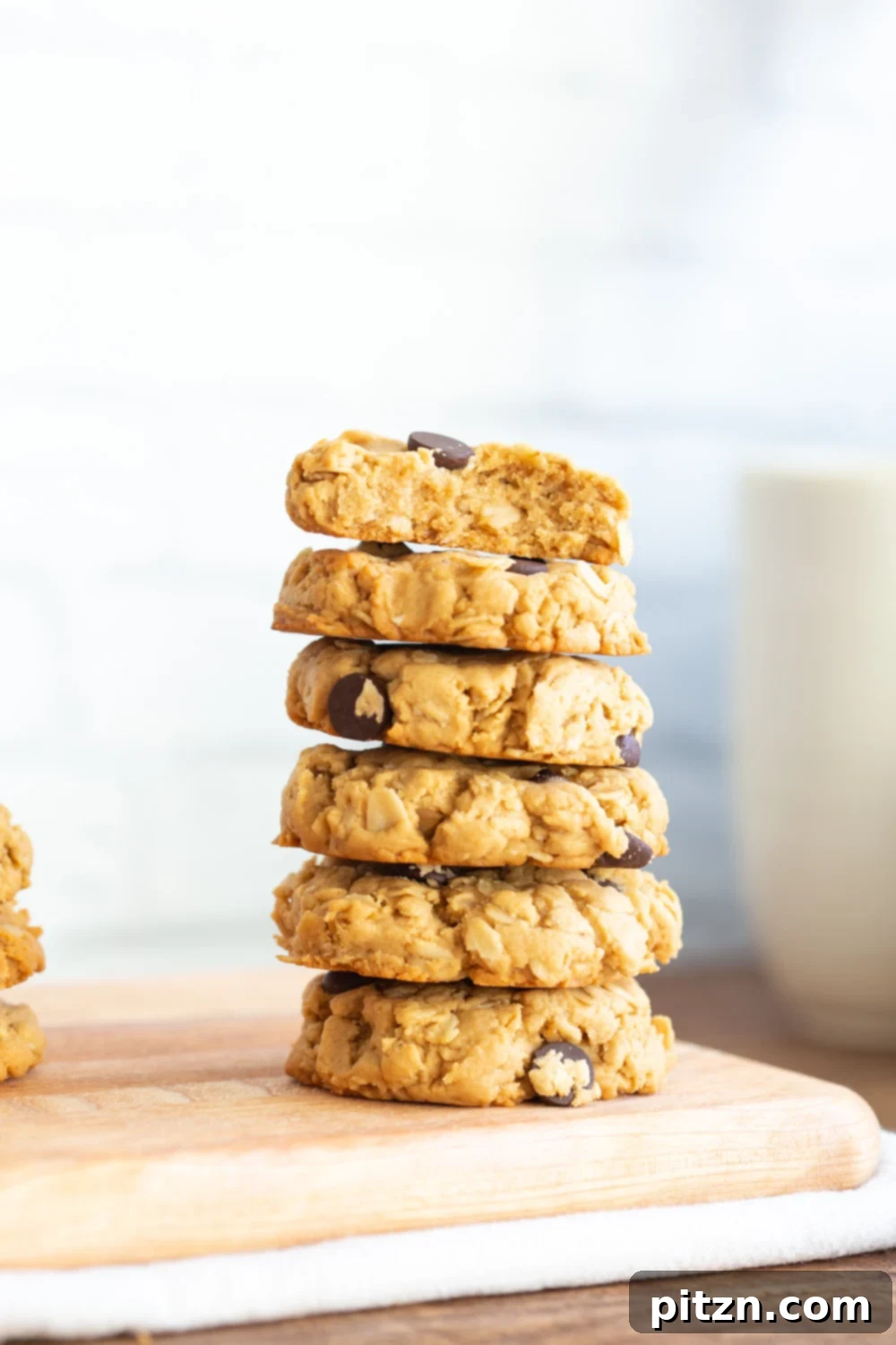 Easy One-Bowl Vegan Peanut Butter Oatmeal Chocolate Chip Cookies 11 A stack of golden-brown Vegan Peanut Butter Oatmeal Chocolate Chip Cookies, showing their inviting texture and rich chocolate, on a wooden surface.