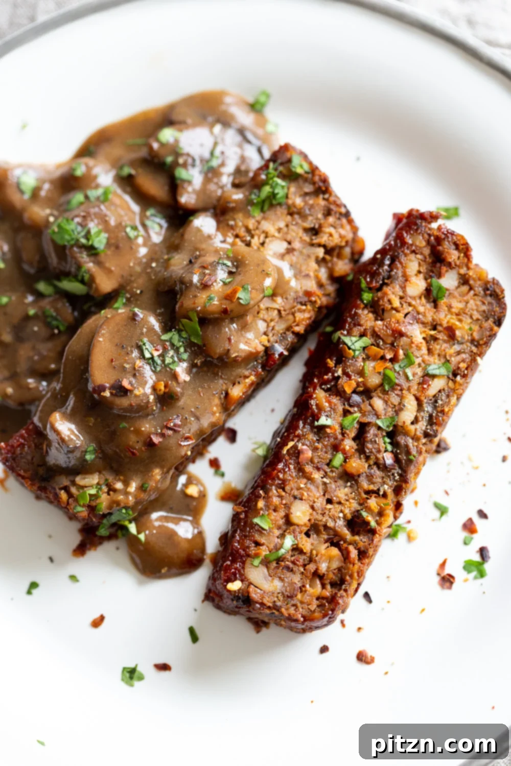 A perfectly sliced serving of vegan nut loaf, drizzled with mushroom gravy, ready to enjoy.