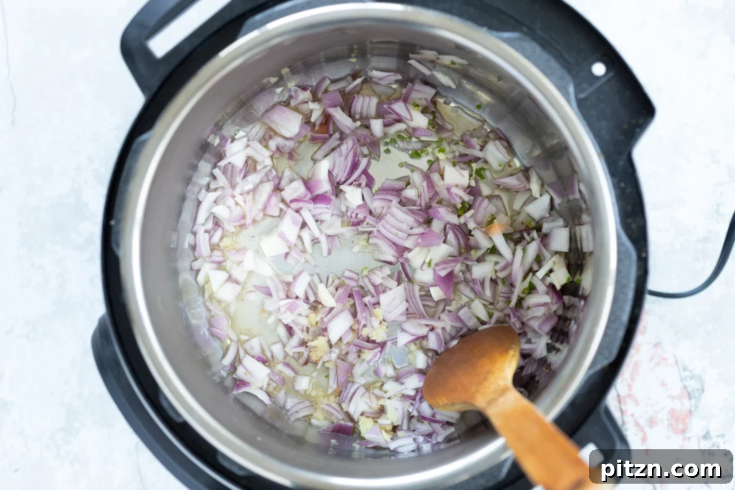 Sautéing the aromatic base for our Vegan Lentil Soup in an Instant Pot. Onions, garlic, and ginger are gently cooking, releasing their fragrant oils and building the foundational flavor for this comforting and healthy dish. | VeganRicha.com