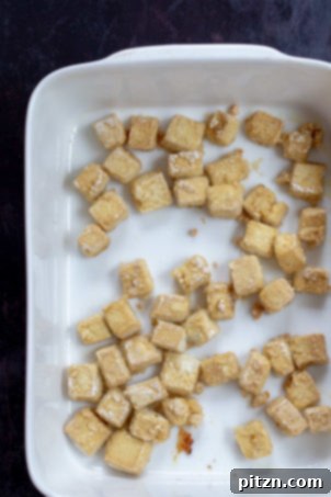 Baked Tofu cubes in a white baking dish for our Crispy Orange Tofu Recipe