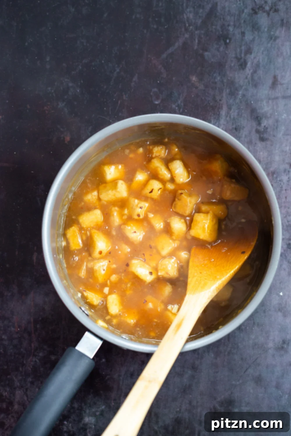 Baked Tofu mixed with Orange Sauce in a saucepan, part of our Easy Orange Tofu Recipe