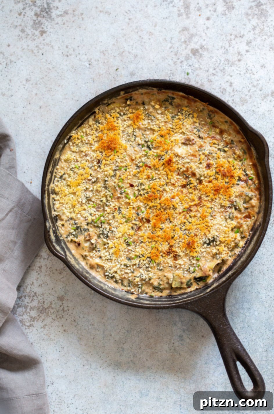 A vibrant cast iron skillet filled with creamy Vegan Spinach Artichoke Dip, ready for serving.