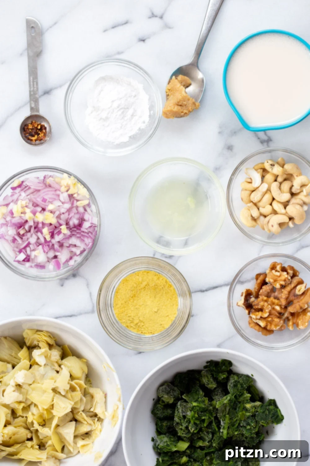 Ingredients for Vegan Spinach Artichoke Dip laid out in individual bowls and measuring cups, ready for cooking.