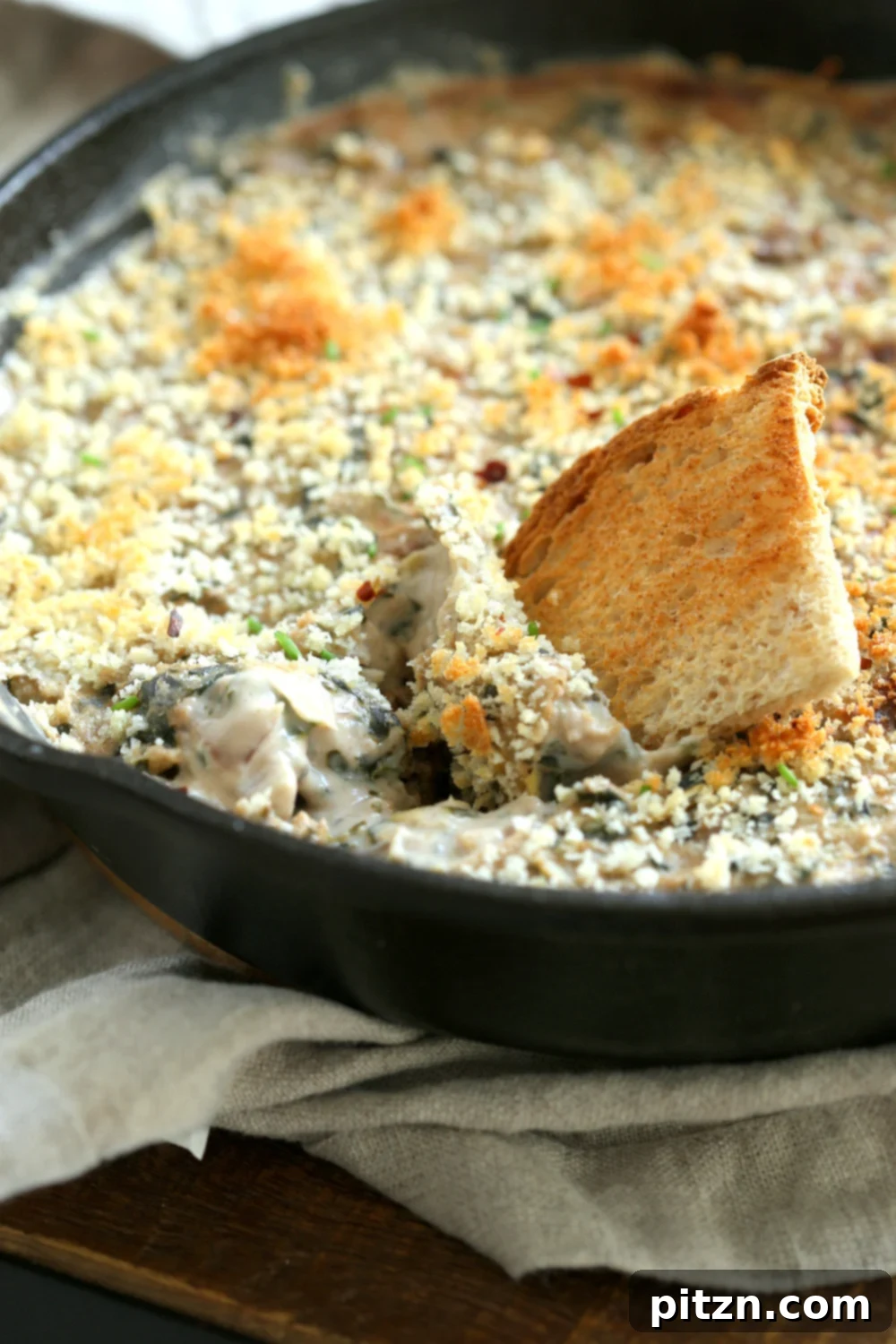 The finished Vegan Spinach Artichoke Dip, golden and bubbling in a cast iron skillet, perfectly cooked and ready to serve.