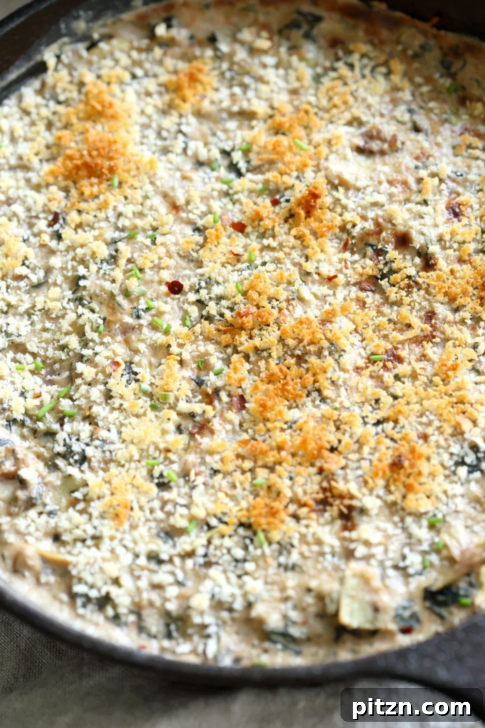 The golden and bubbling Vegan Spinach Artichoke Dip, freshly broiled in a cast iron skillet, looks utterly irresistible.