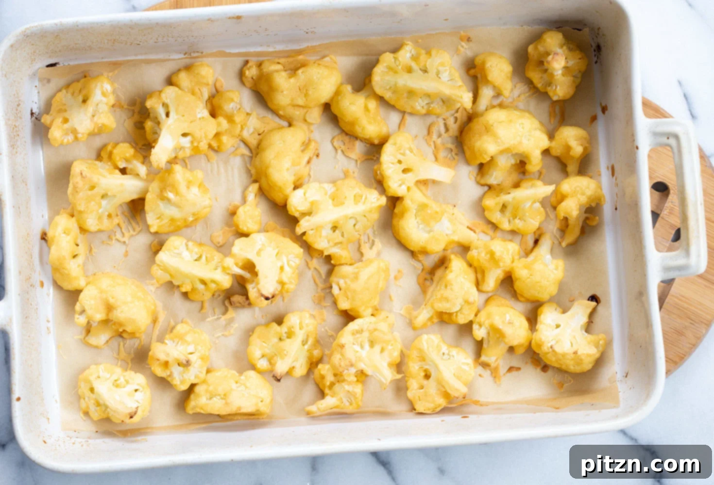 Nashville Heat Vegan Cauliflower Poppers 7 Freshly baked Vegan Nashville Hot Cauliflower Wings in a white baking dish, showing their crispy, golden exterior before being tossed in the signature hot sauce.