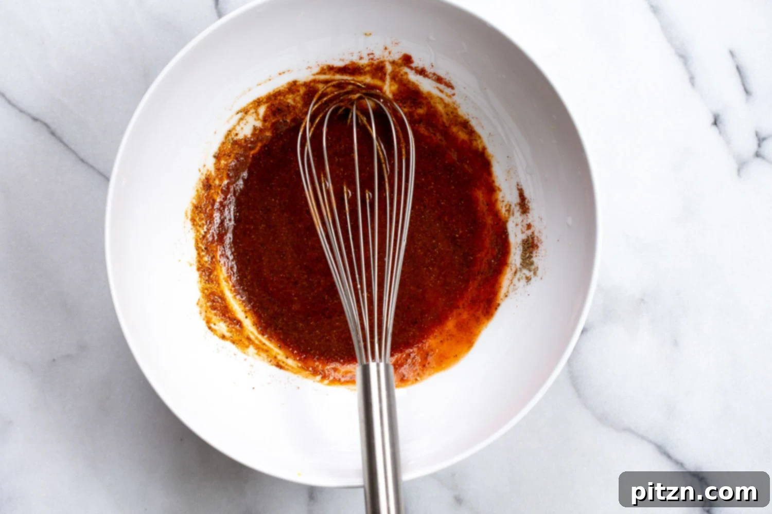 The vibrant red Nashville Hot 'Chikin' Sauce, a spicy and aromatic blend ready to coat the crispy Vegan Nashville Hot Cauliflower Wings, promising an explosion of flavor.