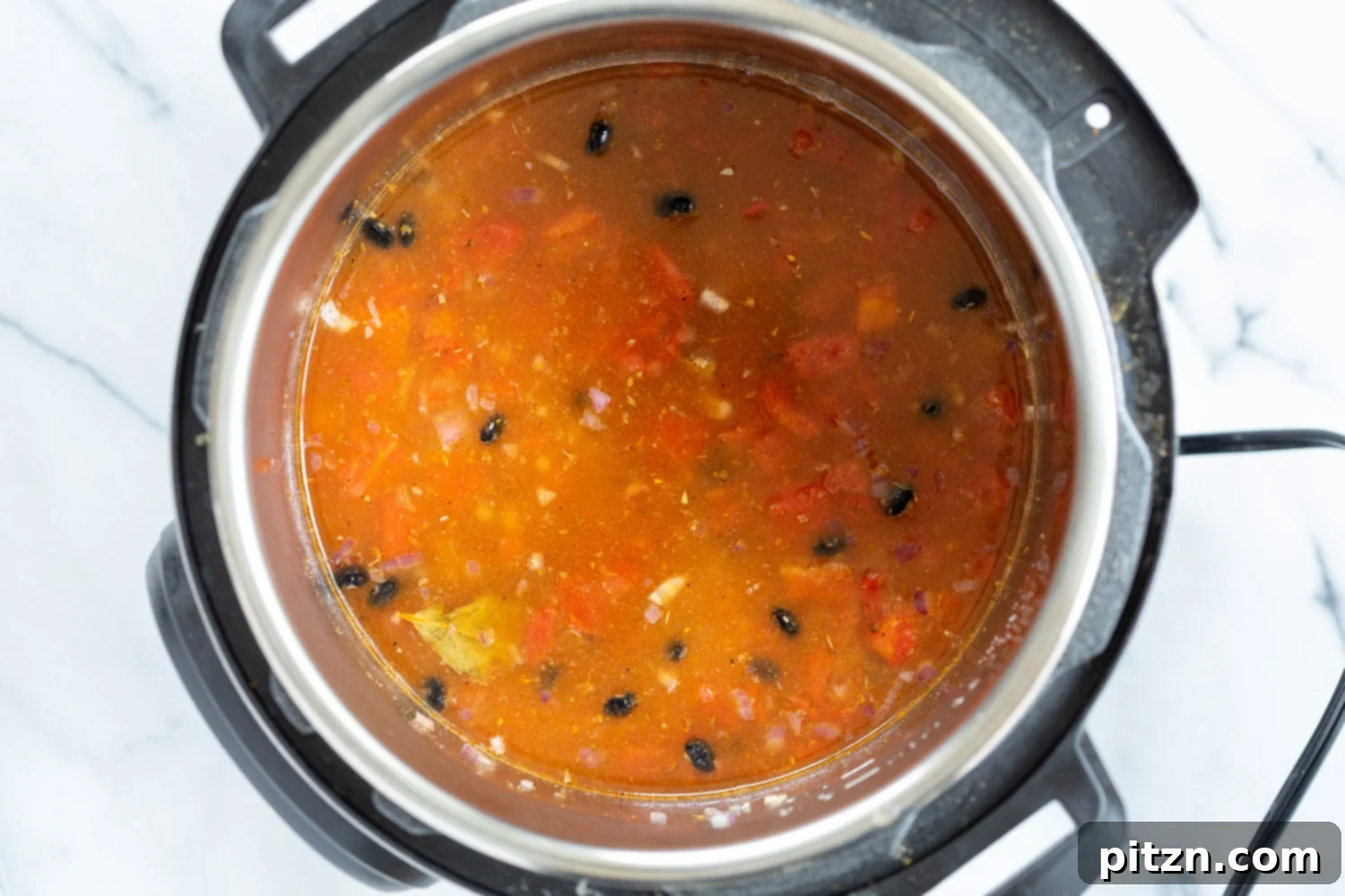 vegan black bean soup dried soaked beans being added to an Instant Pot filled with seasoned tomato broth