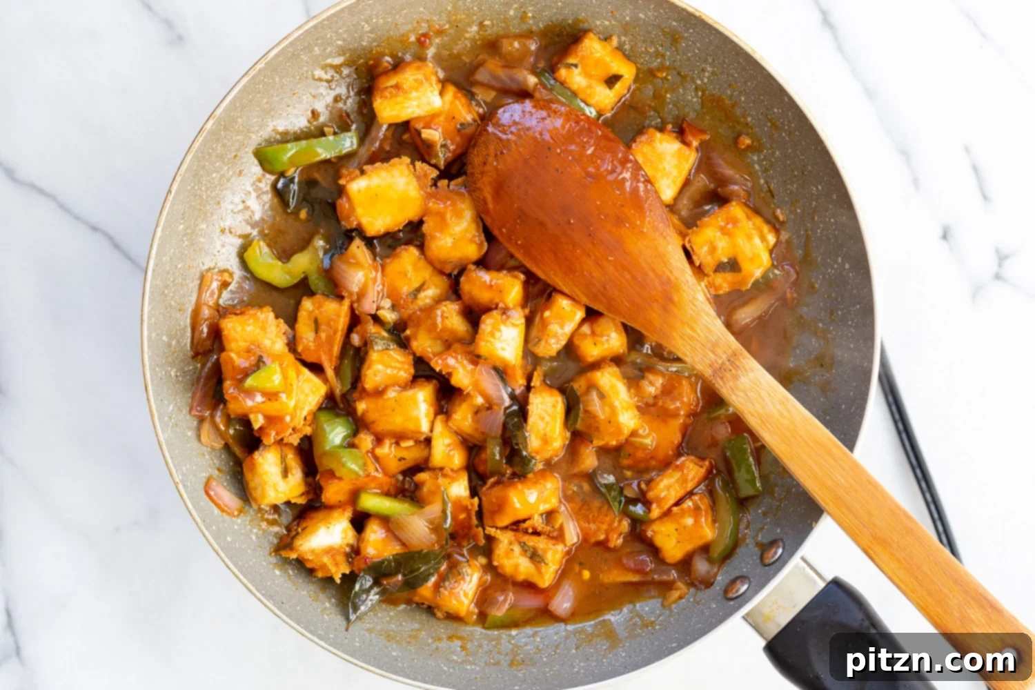 A wide shot of the finished Tofu 65 in a grey skillet, showcasing the full dish, rich in color and texture, ready to be served.