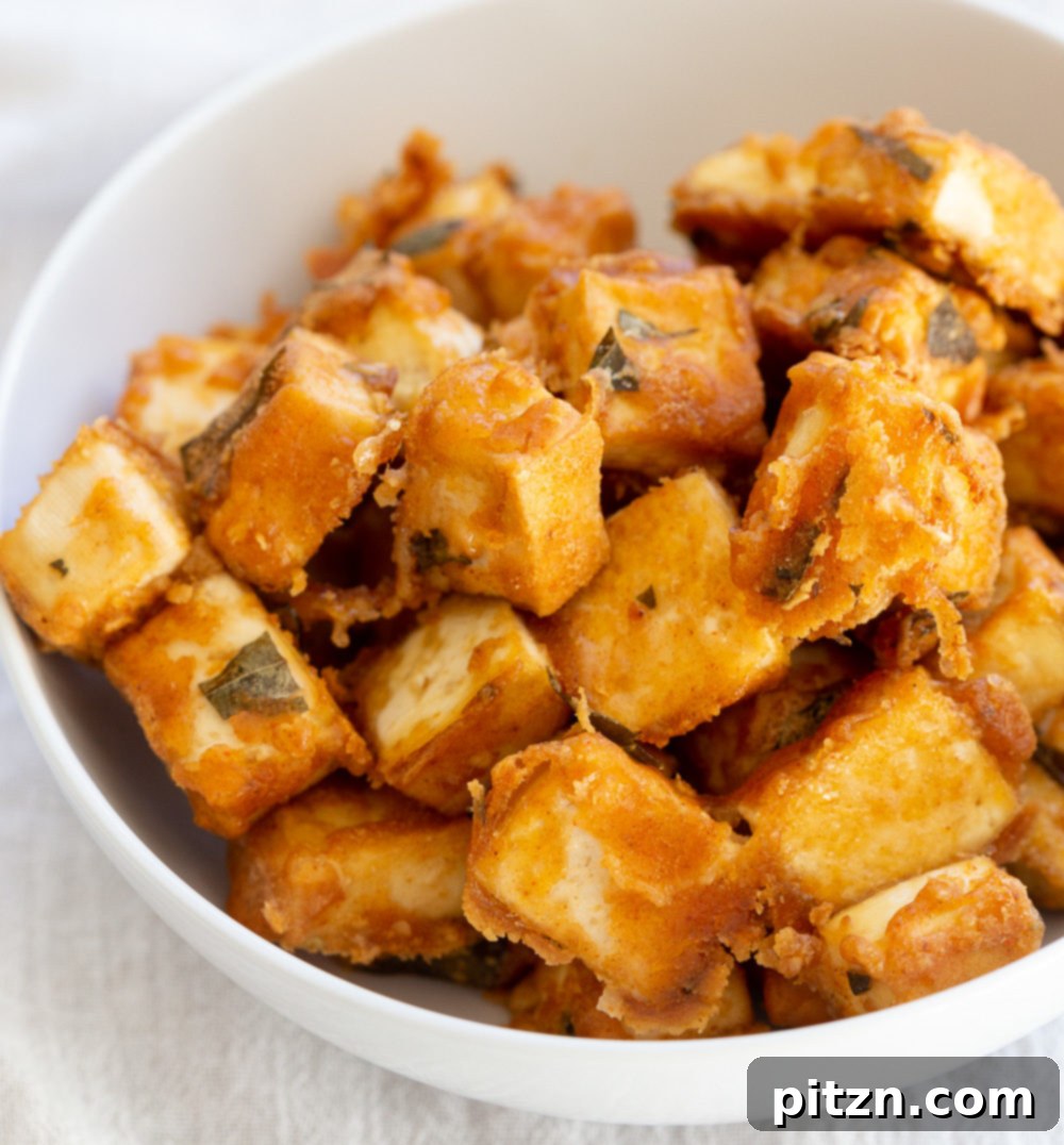 A beautiful presentation of Tofu 65 in a white bowl, with crispy tofu generously coated in a rich, vibrant sauce, garnished with fresh cilantro, ready to be enjoyed.