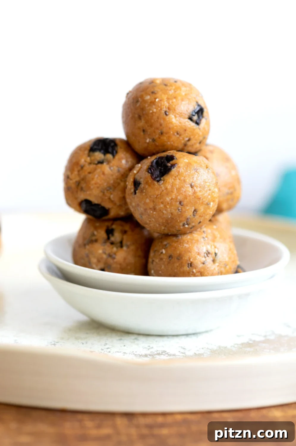 Delicious Vegan Blueberry Muffin Energy Bites arranged on a white surface, showcasing their soft, cakey texture and blueberry speckles. Perfect for a quick, healthy snack or breakfast.