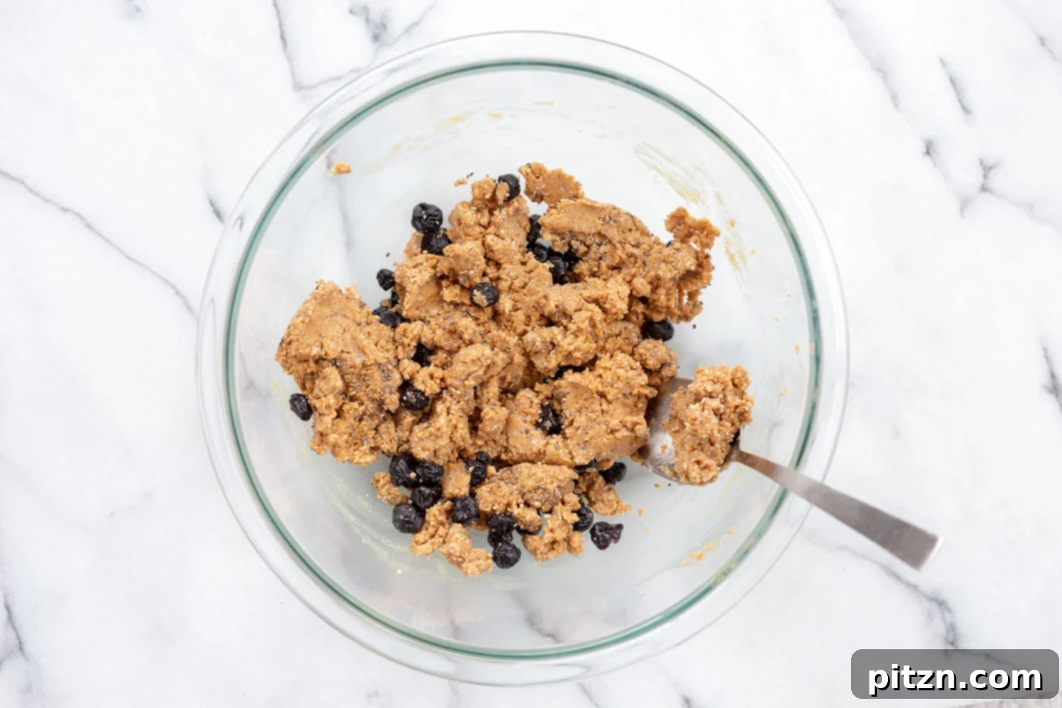 The fully mixed dough for Vegan Blueberry Muffin Energy Bites in a white bowl, featuring visible blueberries and a perfect consistency.